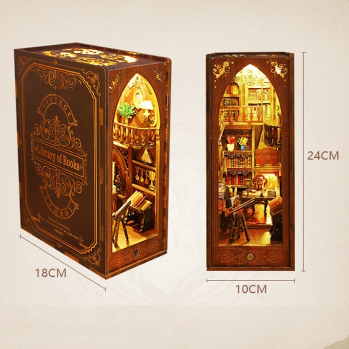 May include: A miniature wooden dollhouse shaped like a book with a detailed interior, including a library, a staircase, and a telescope. The dollhouse is 18 inches wide, 10 inches deep, and 24 inches tall. The front of the dollhouse features a book cover with the text "Vintage Library of Books".