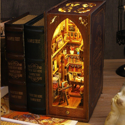May include: A wooden book-shaped box with a miniature library scene inside. The box is lit from within, illuminating the shelves of books, a desk, and a chair. The box is made to look like a vintage book with a brown leather cover and gold lettering.