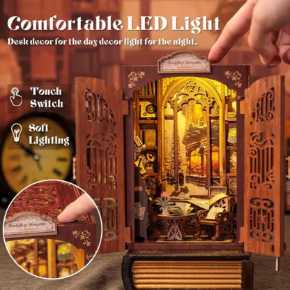 May include: A wooden book-shaped box with a miniature scene inside. The box is open, revealing a detailed miniature of a bookshop with a window, shelves, and furniture. The box has a touch-sensitive switch for soft lighting.