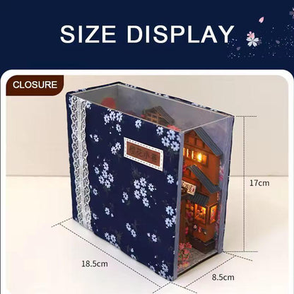 May include: A miniature Japanese-style house diorama, enclosed in a clear box with a navy blue floral patterned cover. The box measures 18.5cm x 8.5cm x 17cm. The diorama features a detailed facade with lit windows and a small garden.