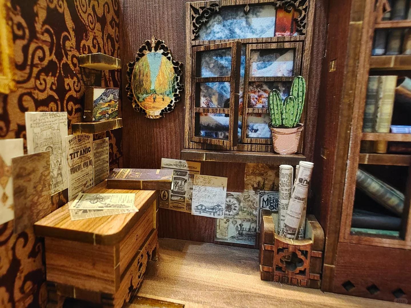 May include: A miniature dollhouse room with a wooden bookcase, a window with a snowy scene, a small wooden chest, and a framed picture of a forest. The room is decorated with vintage-style wallpaper and ephemera.