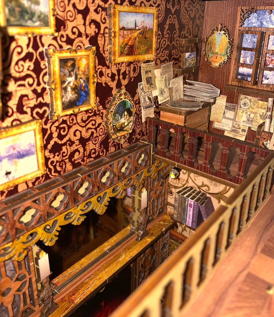 May include: A miniature dollhouse interior with a wooden staircase, a balcony, and a room with a fireplace and framed artwork. The walls are covered in a dark red patterned wallpaper.