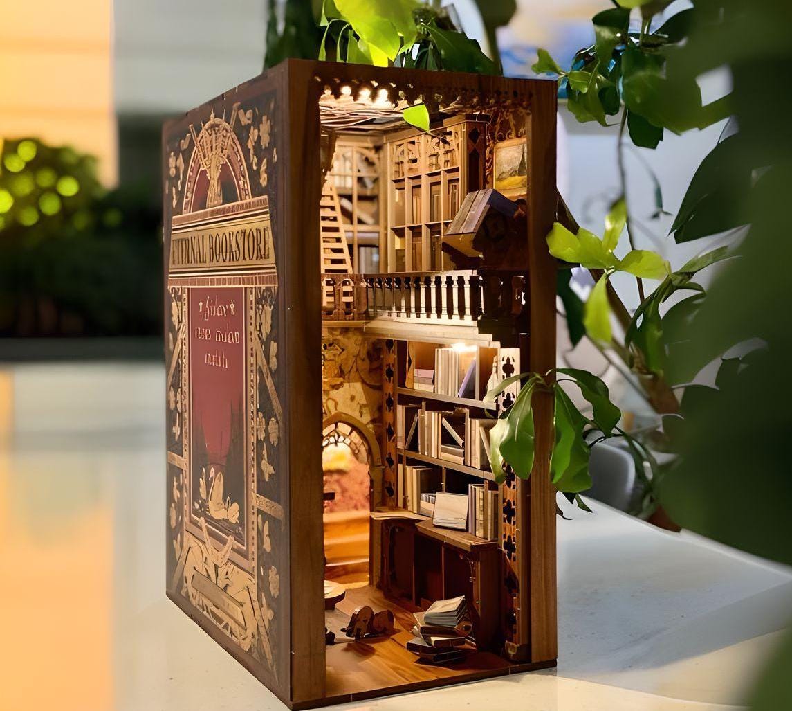 May include: A miniature wooden bookshelf diorama, crafted to resemble a book. The front cover features a vintage design with the text "Eternal Bookstore" and intricate floral patterns. The interior is lit and shows a multi-level bookshelf filled with miniature books.