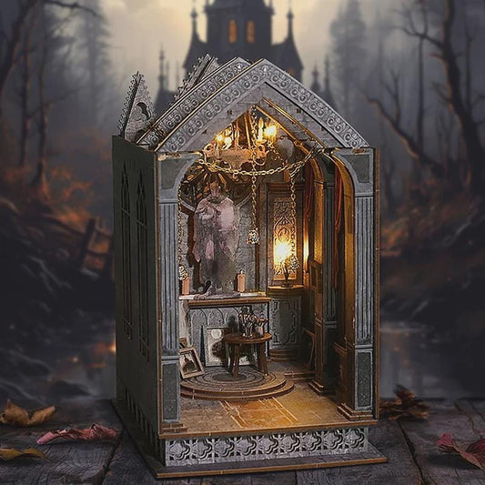 May include: A miniature gothic-style diorama with a detailed interior, featuring a statue, small table, and ornate architectural elements. The diorama is illuminated with warm lighting, creating a mysterious atmosphere. The exterior is gray with decorative trim, set against a blurred forest backdrop.