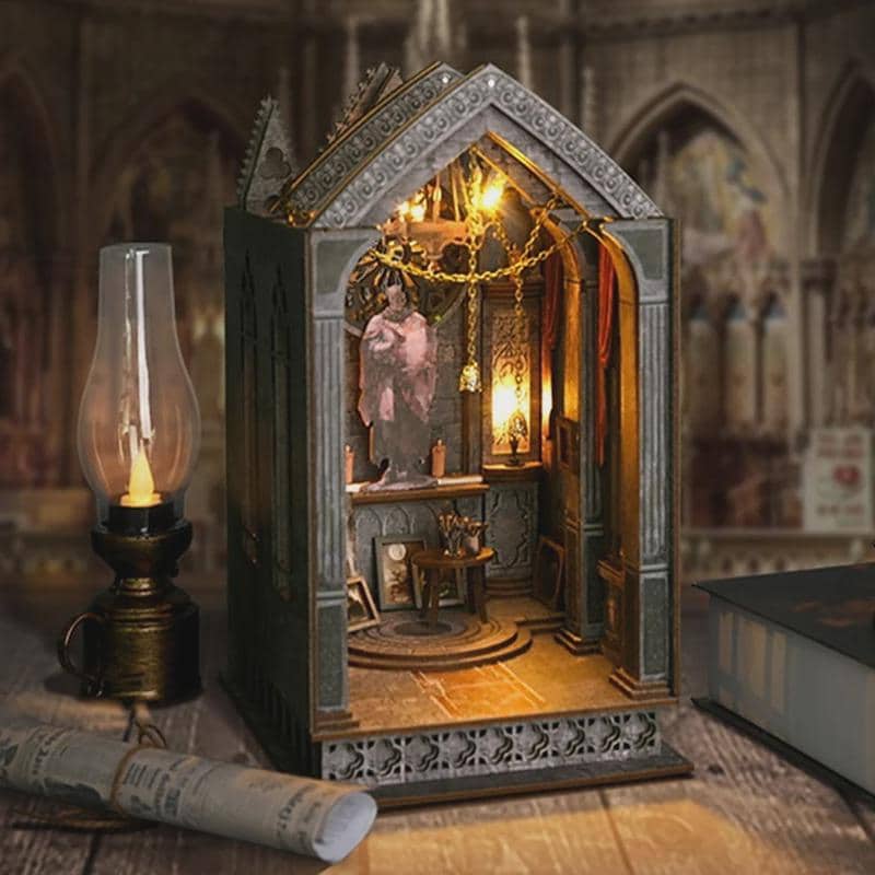May include: A miniature diorama of a gothic cathedral interior, illuminated by warm lights. The detailed scene includes a statue, small table, and decorative elements. A vintage oil lamp and rolled parchment are in the foreground, with a book on the right.