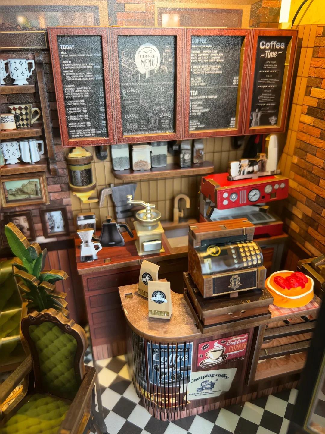 May include: Miniature coffee shop scene with a red espresso machine, coffee menu boards, and a vintage cash register. The scene includes coffee bags, a grinder, and a small green chair. The floor is black and white checkered tile.