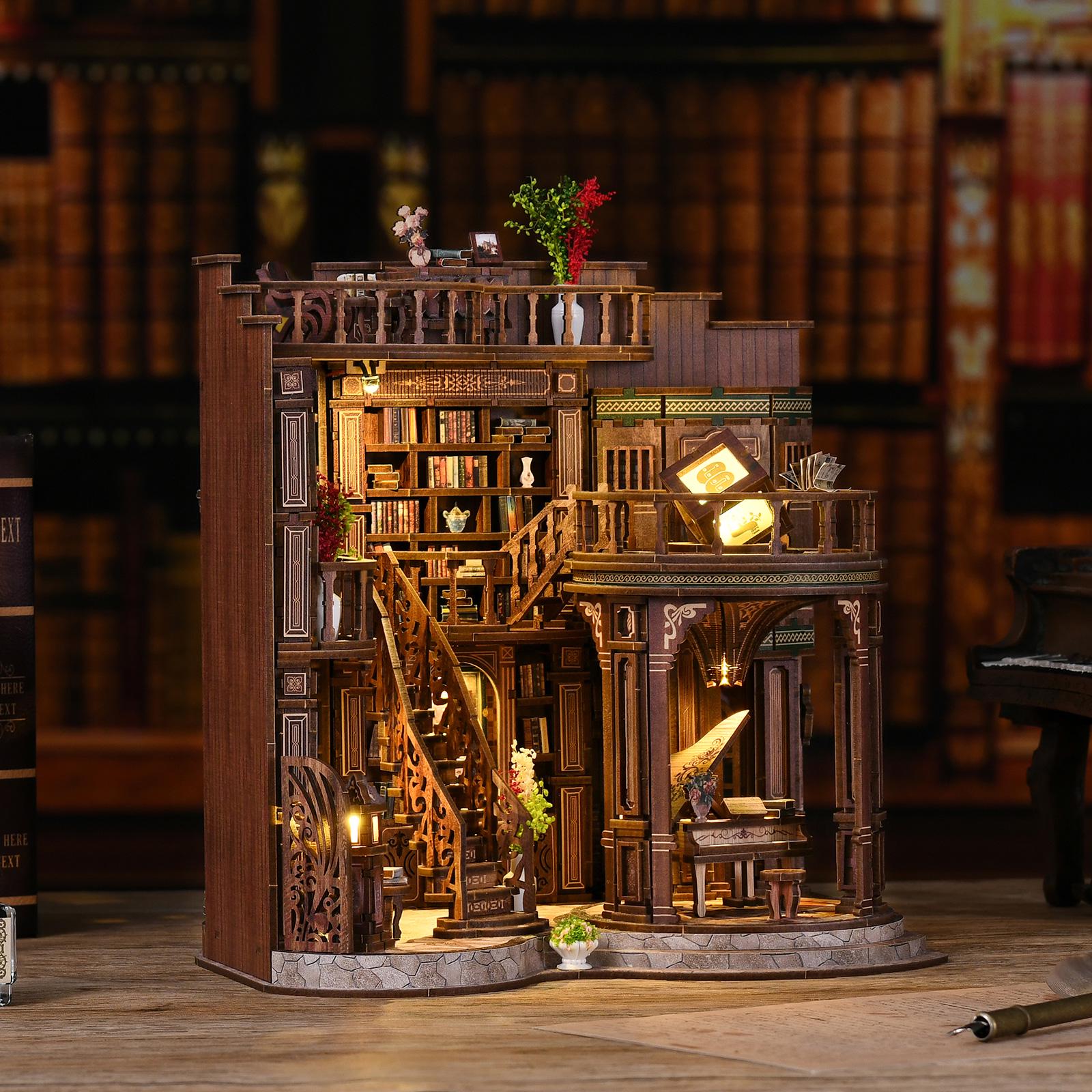 May include: A detailed wooden miniature of a library with multiple levels, stairs, and a piano. The model features intricate carvings, bookshelves filled with tiny books, and warm interior lighting. Decorative flowers and plants add color to the scene.