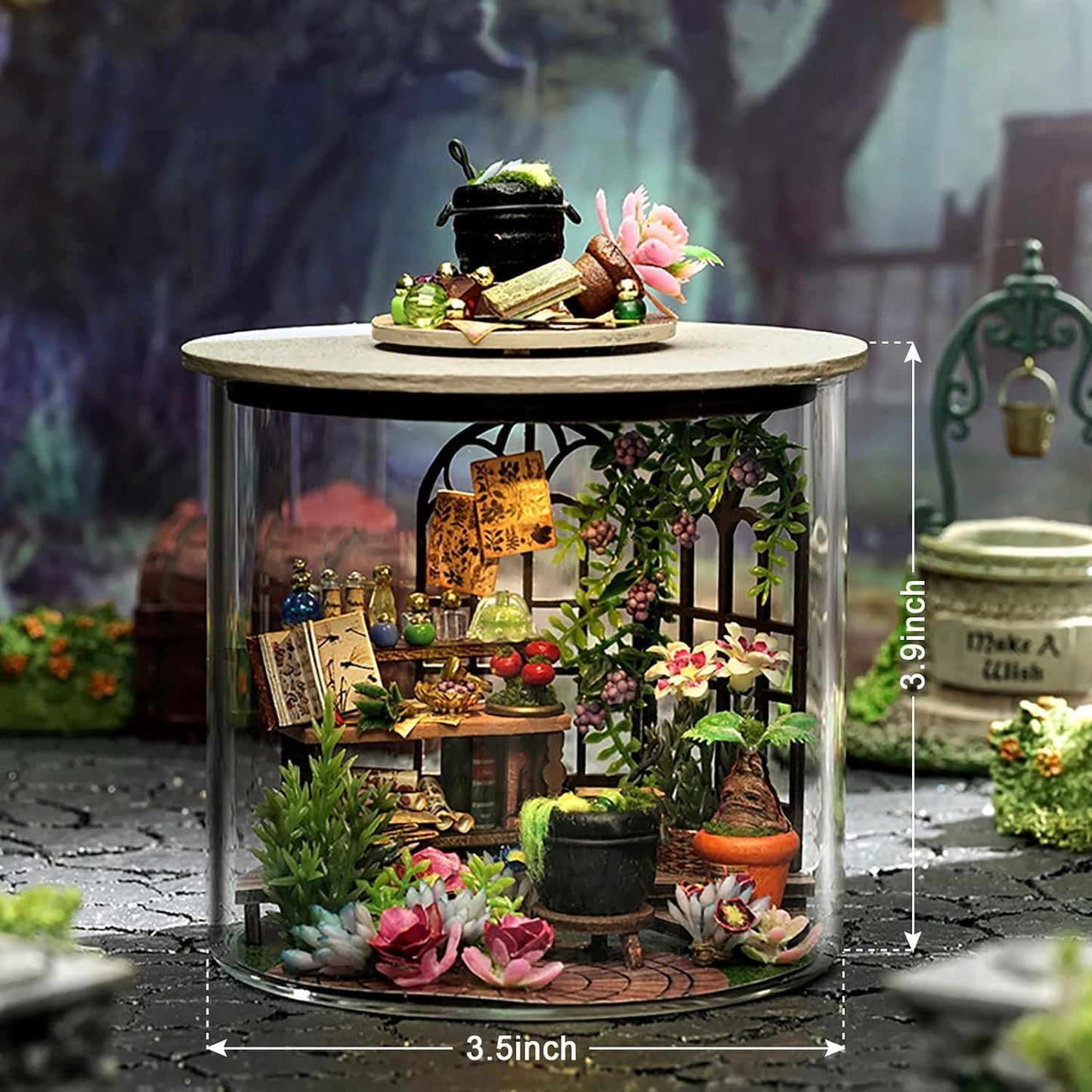 May include: A miniature diorama inside a glass cylinder, featuring a detailed witch's apothecary scene. The scene includes tiny books, bottles, plants, and a cauldron. The cylinder is 3.5 inches wide and 3.9 inches tall.