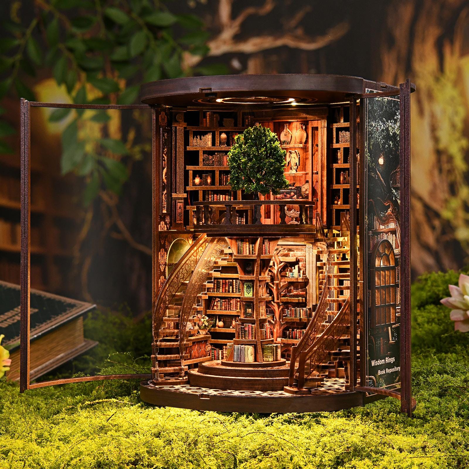 May include: A miniature wooden bookshelf diorama with a detailed interior, including spiral staircases, shelves filled with tiny books, and a small tree. The diorama has a warm, inviting glow from interior lighting, and the text "Wisdom Rings Book Repository" is visible.